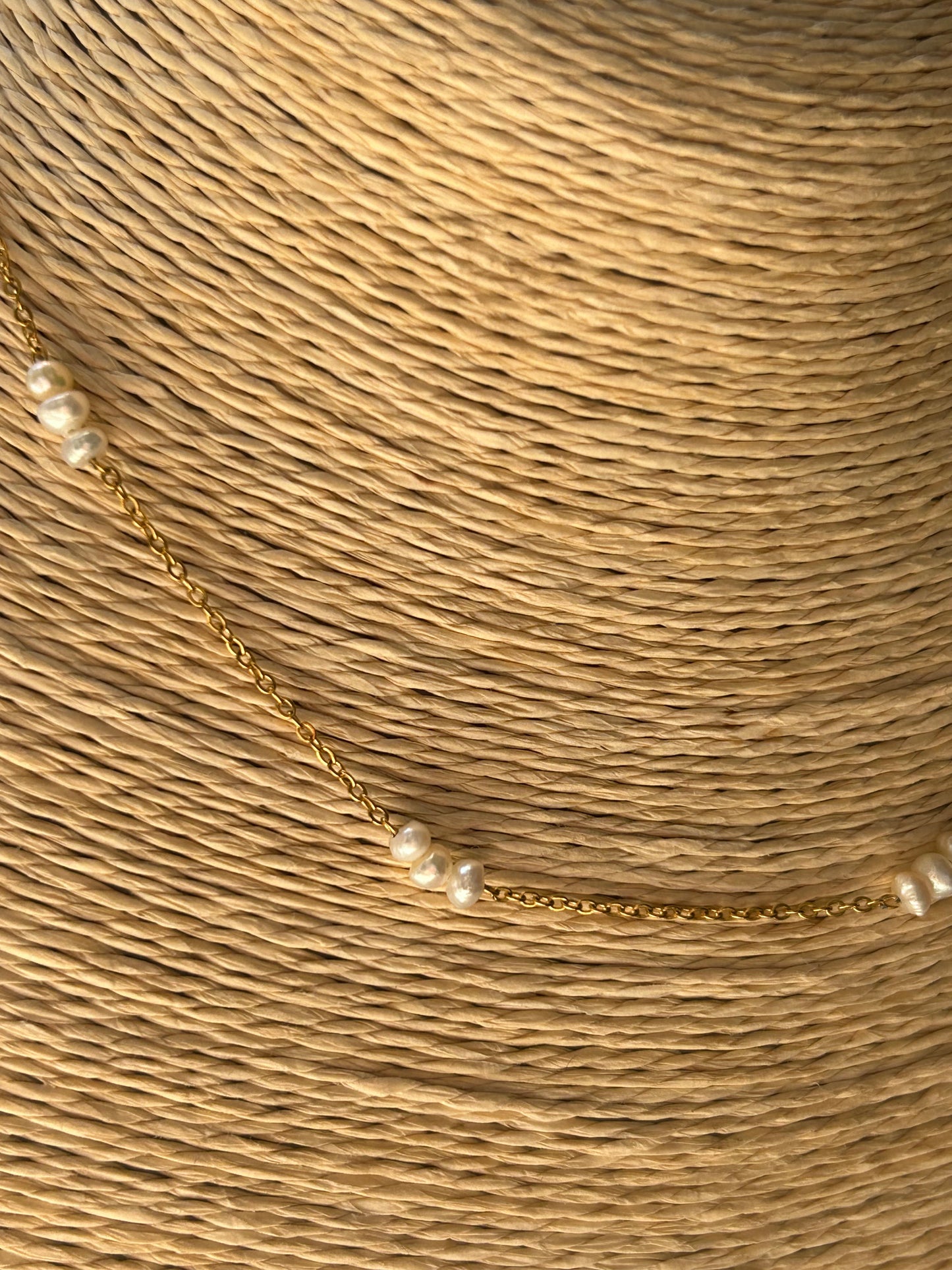 Gold necklace with pearls on a textured beige background