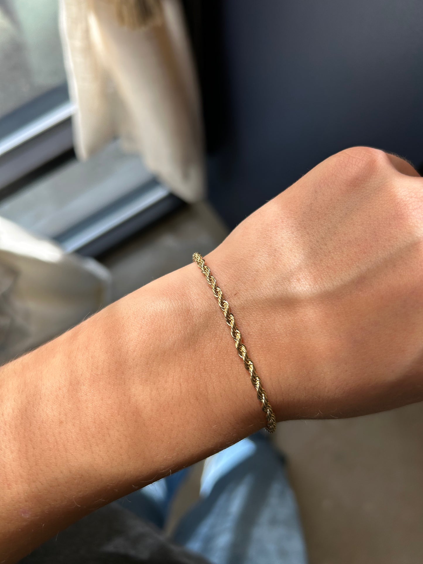 Gold bracelet on a wrist with a blurred background