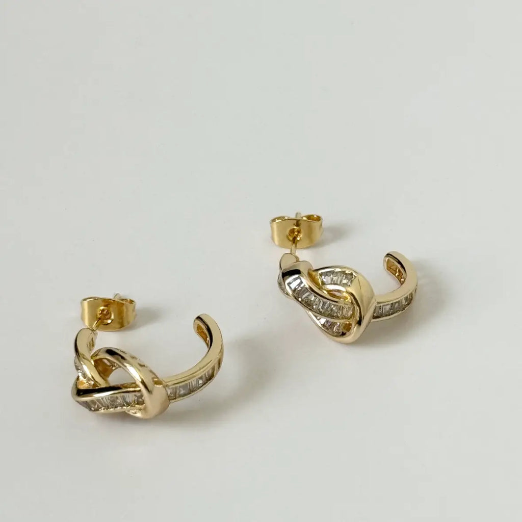 Gold hoop earrings with diamond accents on a light gray background