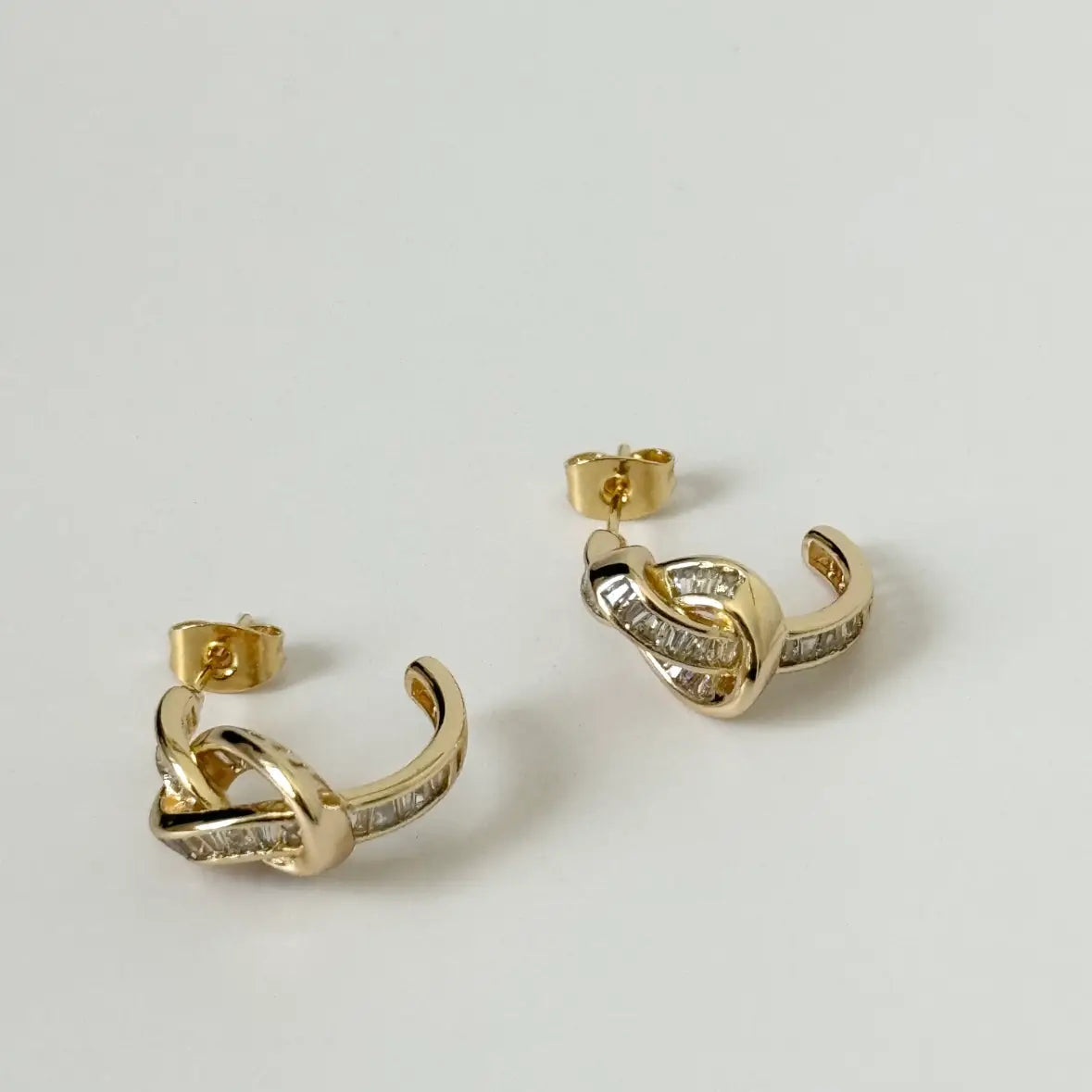 Gold hoop earrings with diamond accents on a light gray background