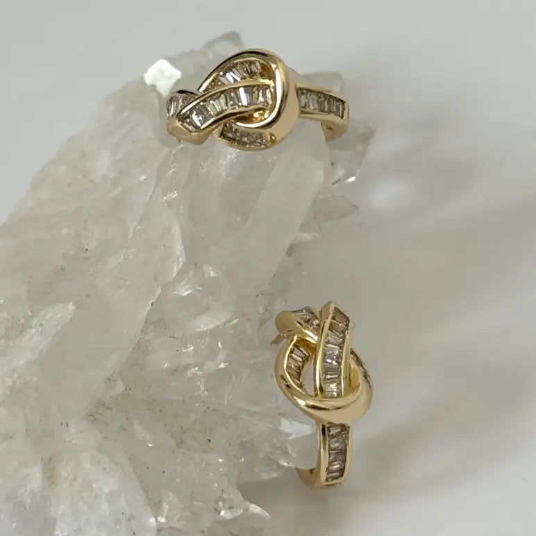 Gold earrings with diamond accents on a crystal background