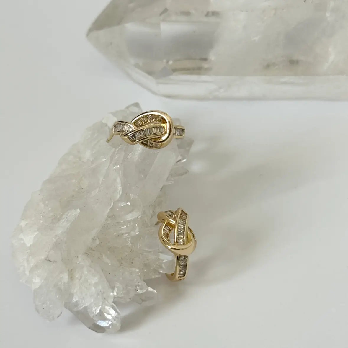 Gold hoop earrings with clear stones on a crystal background