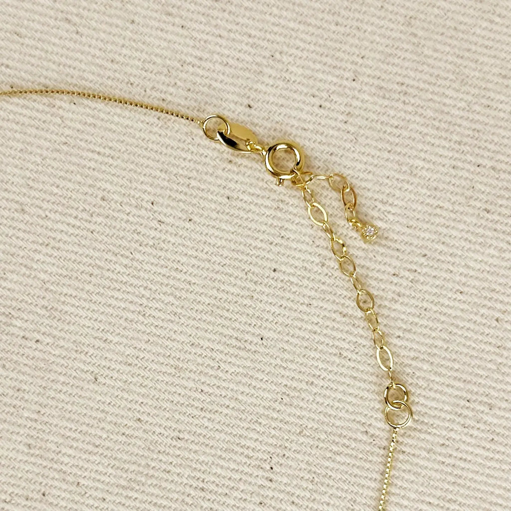 Gold chain necklace on a beige textured background