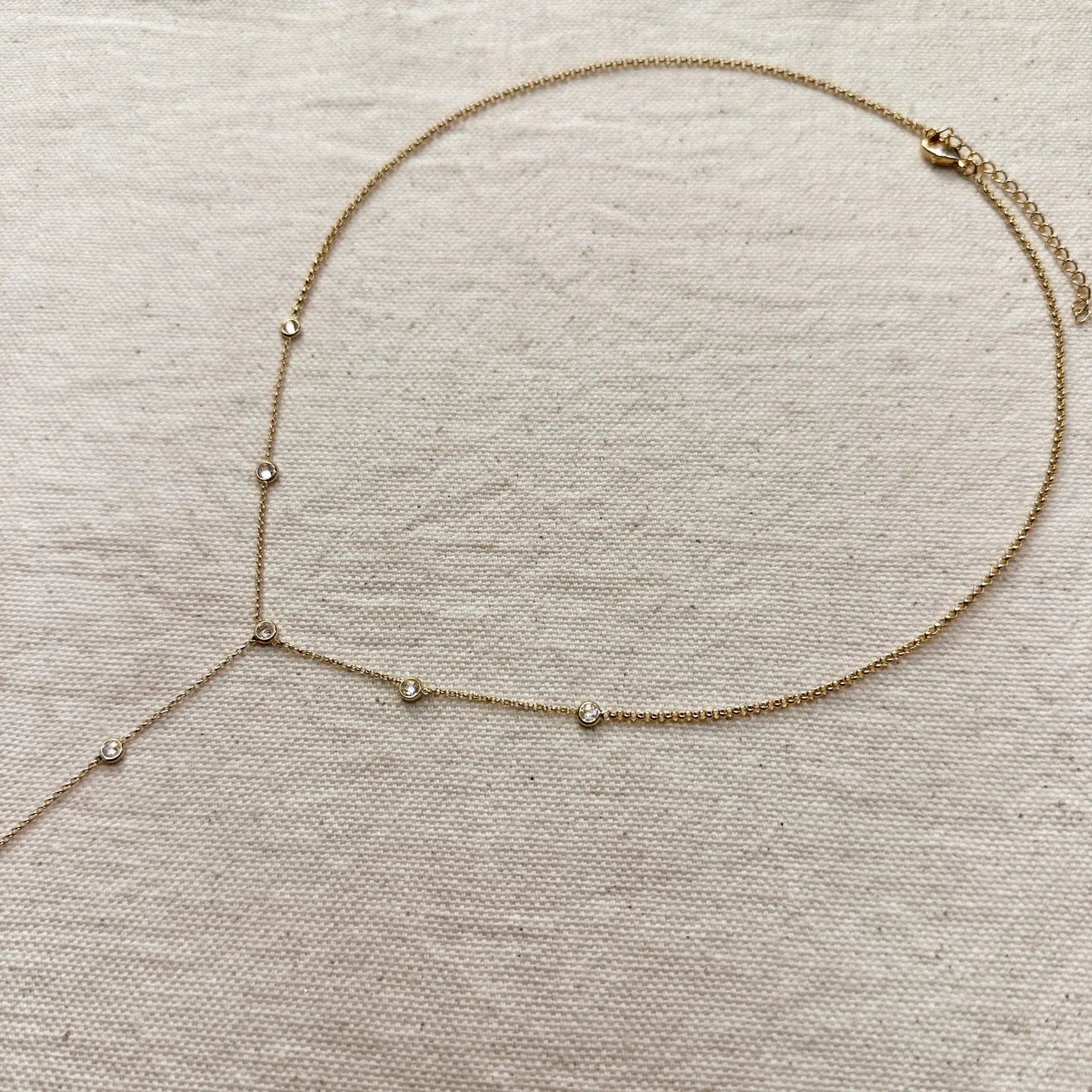 Gold necklace with small beads on a beige fabric background