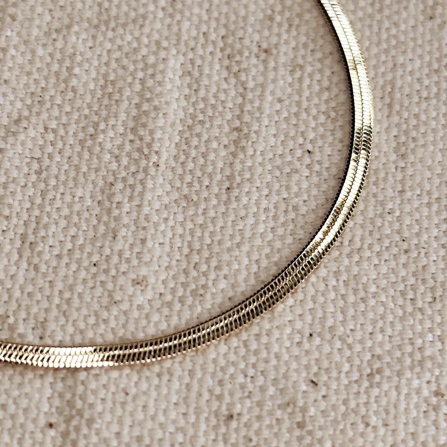 Gold necklace on a beige fabric background