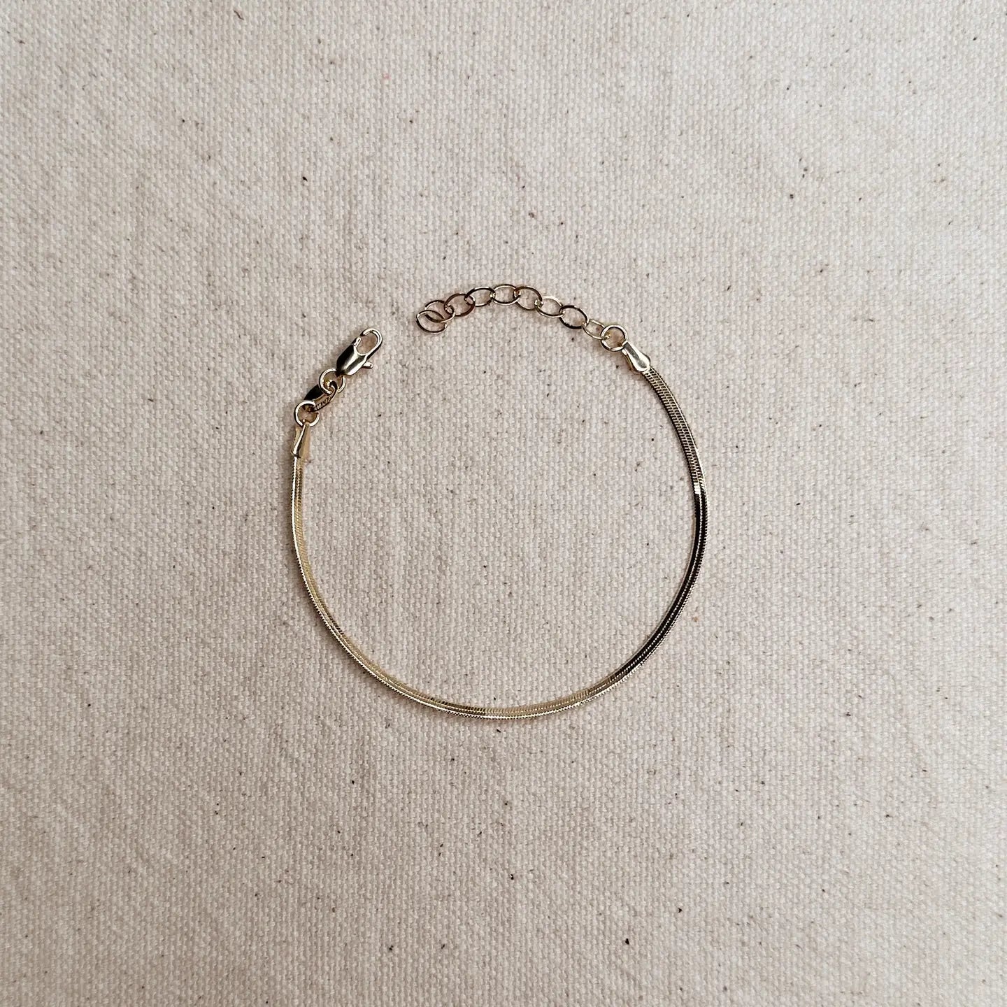 Gold bracelet on a textured beige background