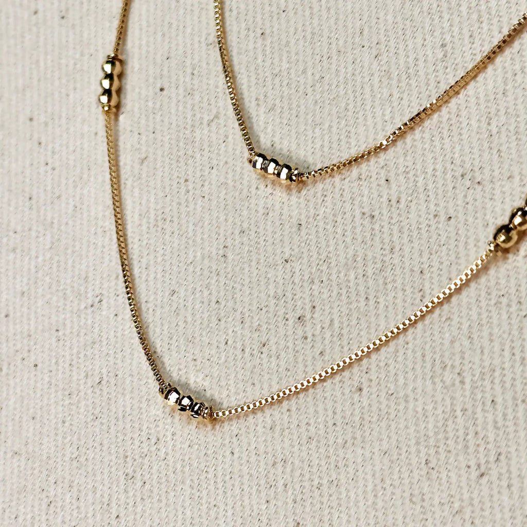 Gold necklace with small beads on a beige fabric background
