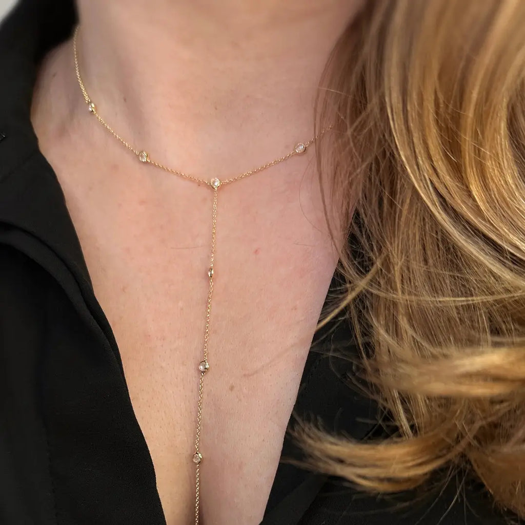 Gold body chain worn by a person with blonde hair, against a black background