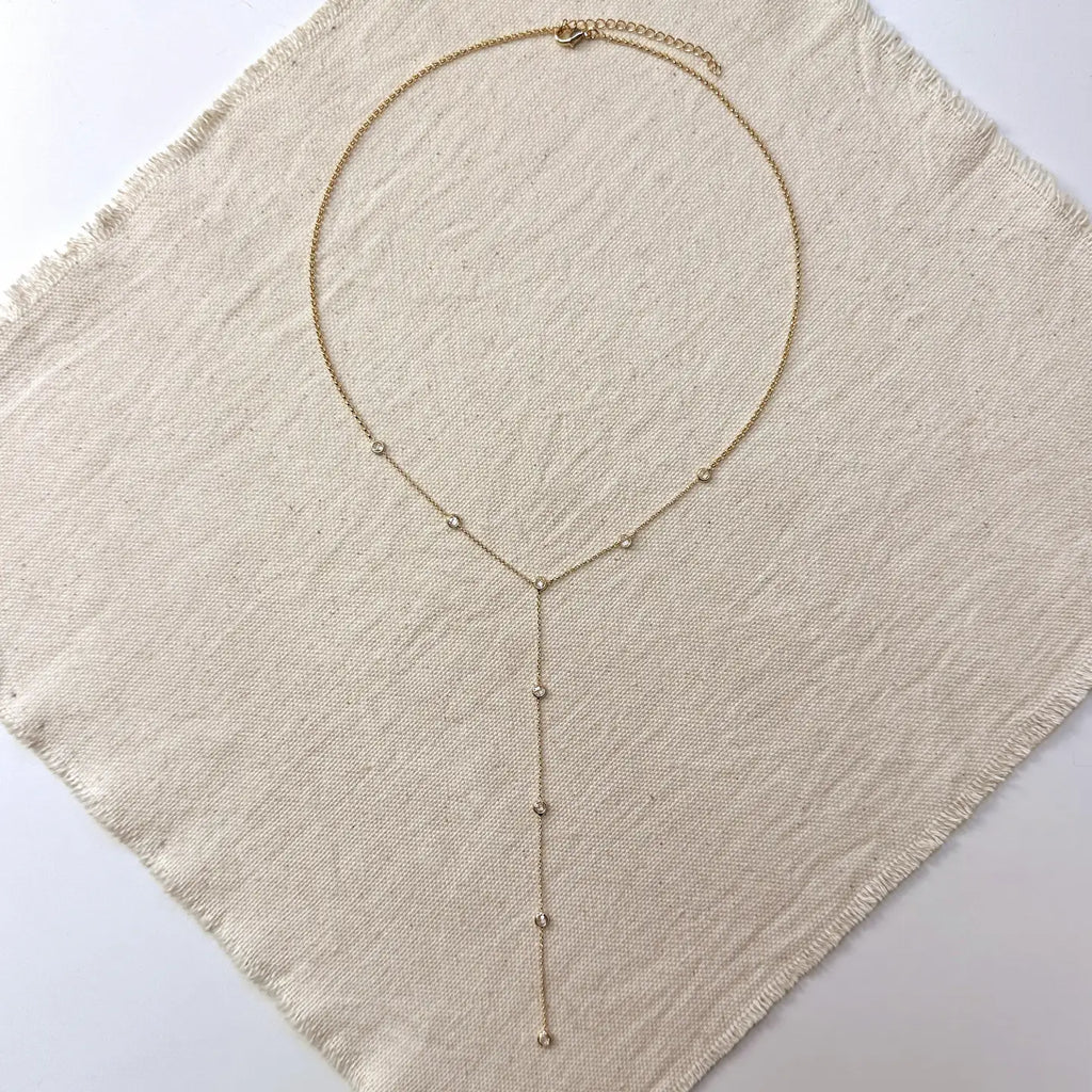 Gold necklace on a textured beige fabric background