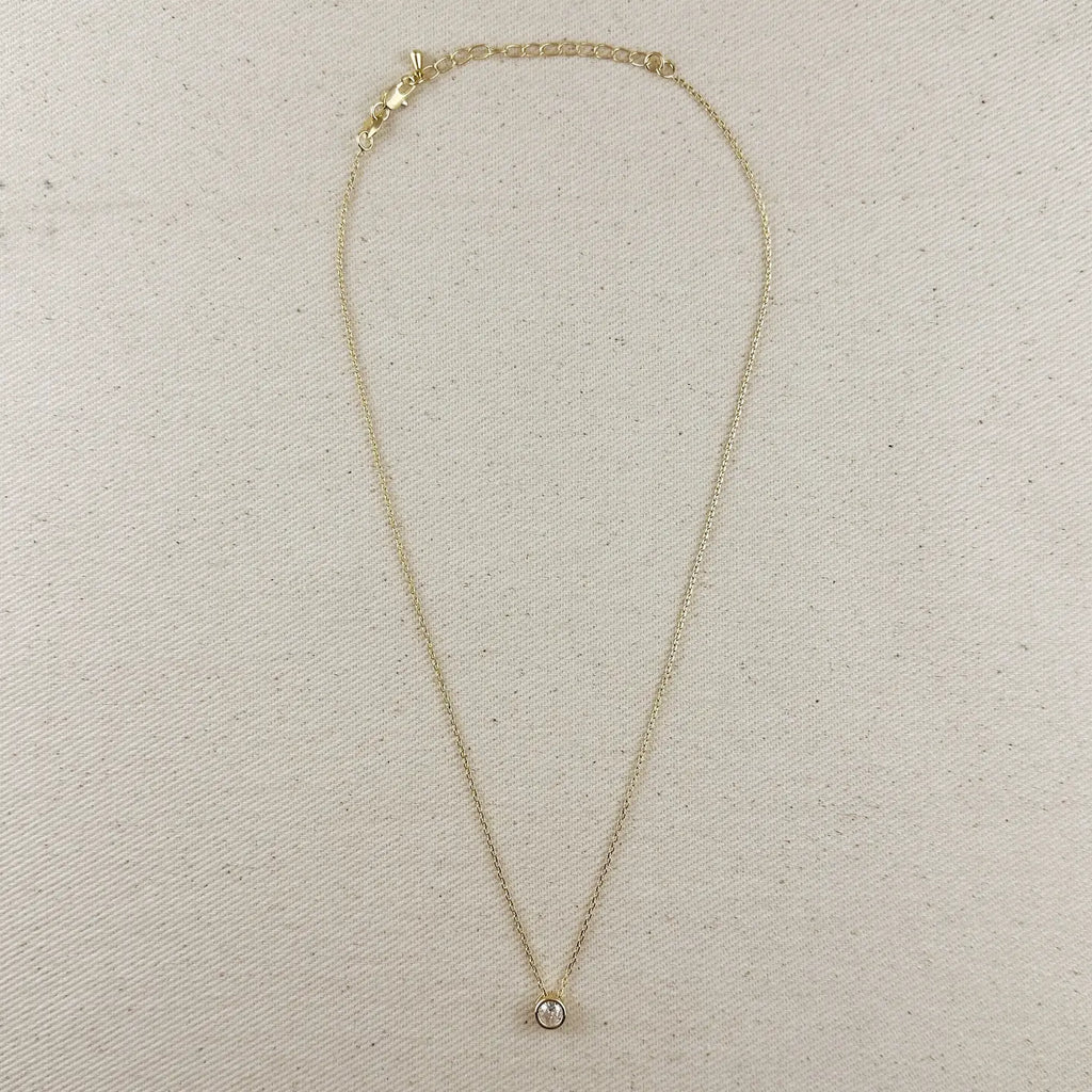 Gold necklace with a small pendant on a beige fabric background