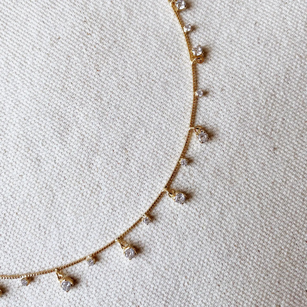 Delicate gold necklace with small diamonds on a light fabric background