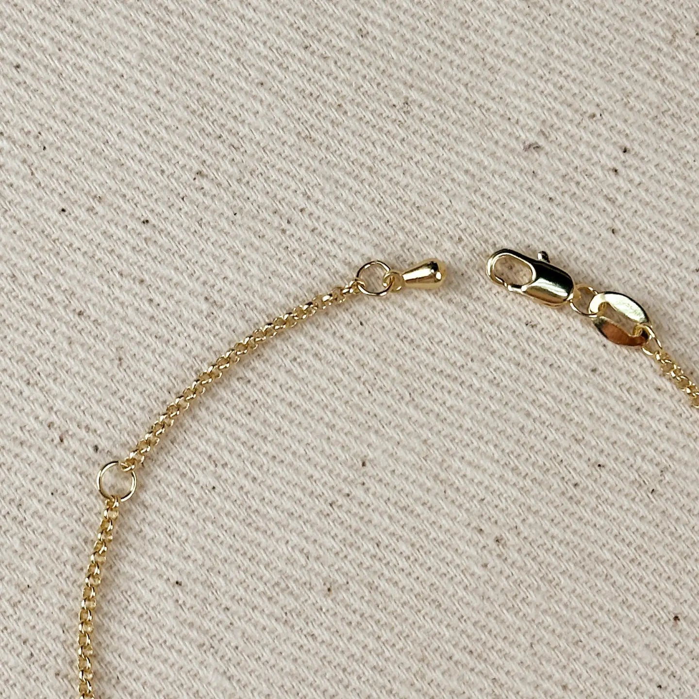 Gold chain with clasp on a beige textured background