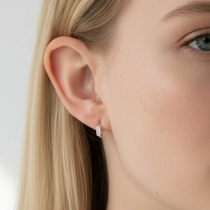 Close-up of a woman wearing diamond stud earrings with a plain background