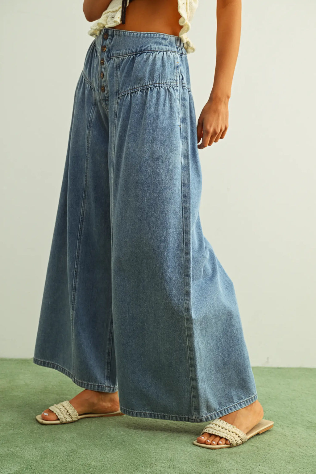 Person wearing a long denim skirt on a plain background