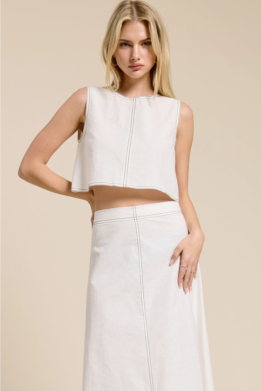 Woman wearing a white sleeveless top and skirt set on a beige background