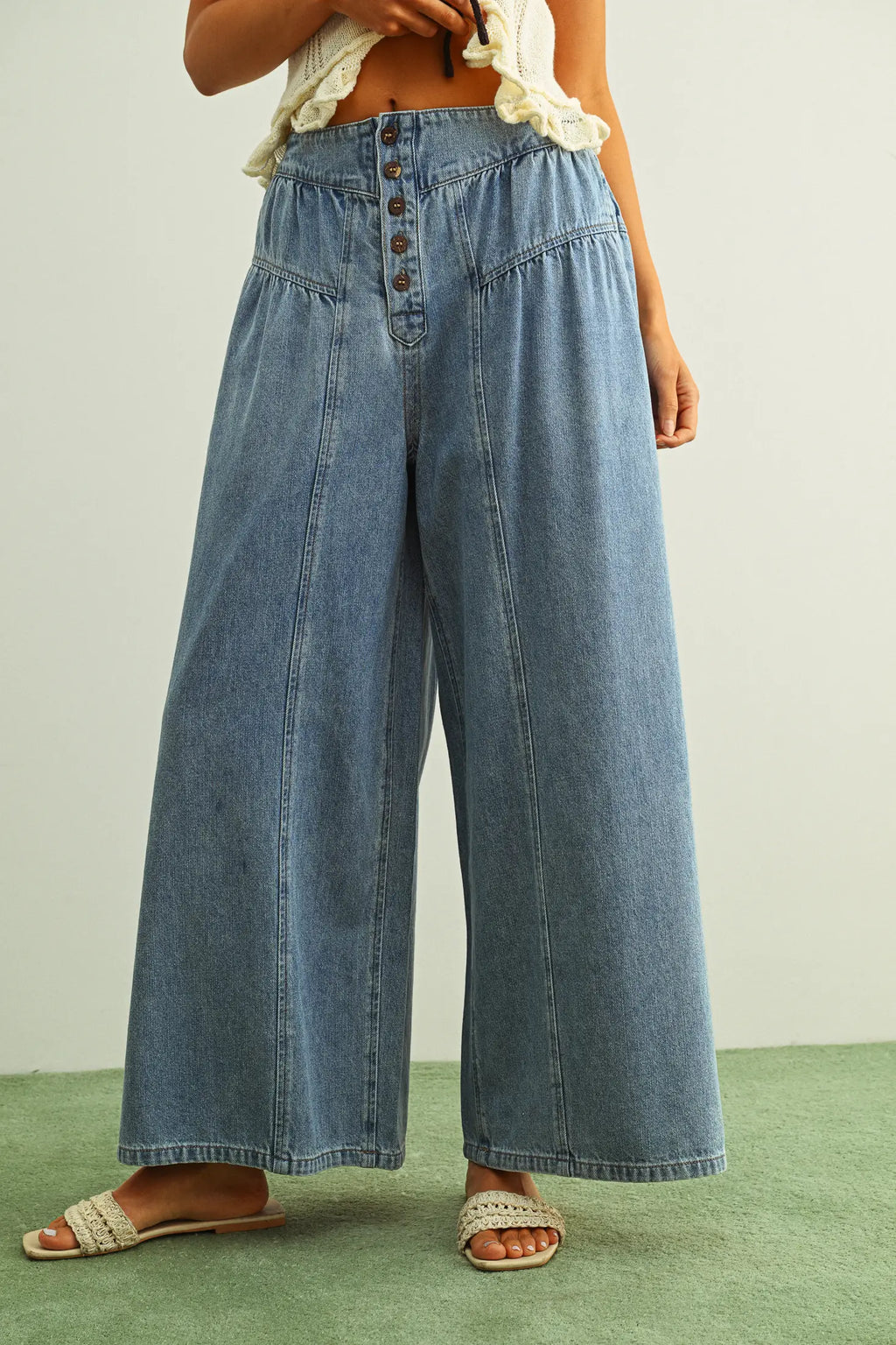 Person wearing blue denim wide-leg pants on a plain background