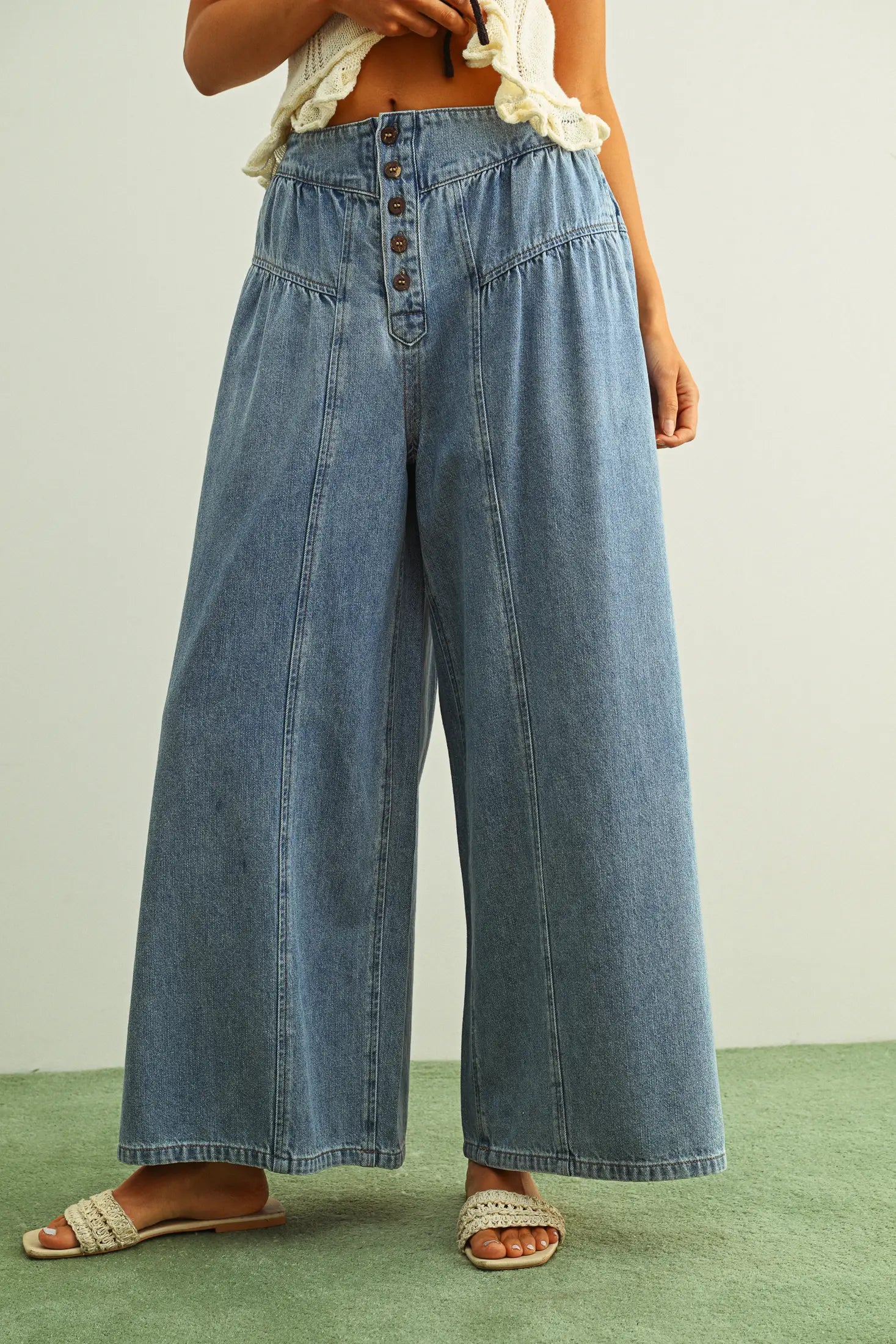 Person wearing blue denim wide-leg pants on a plain background