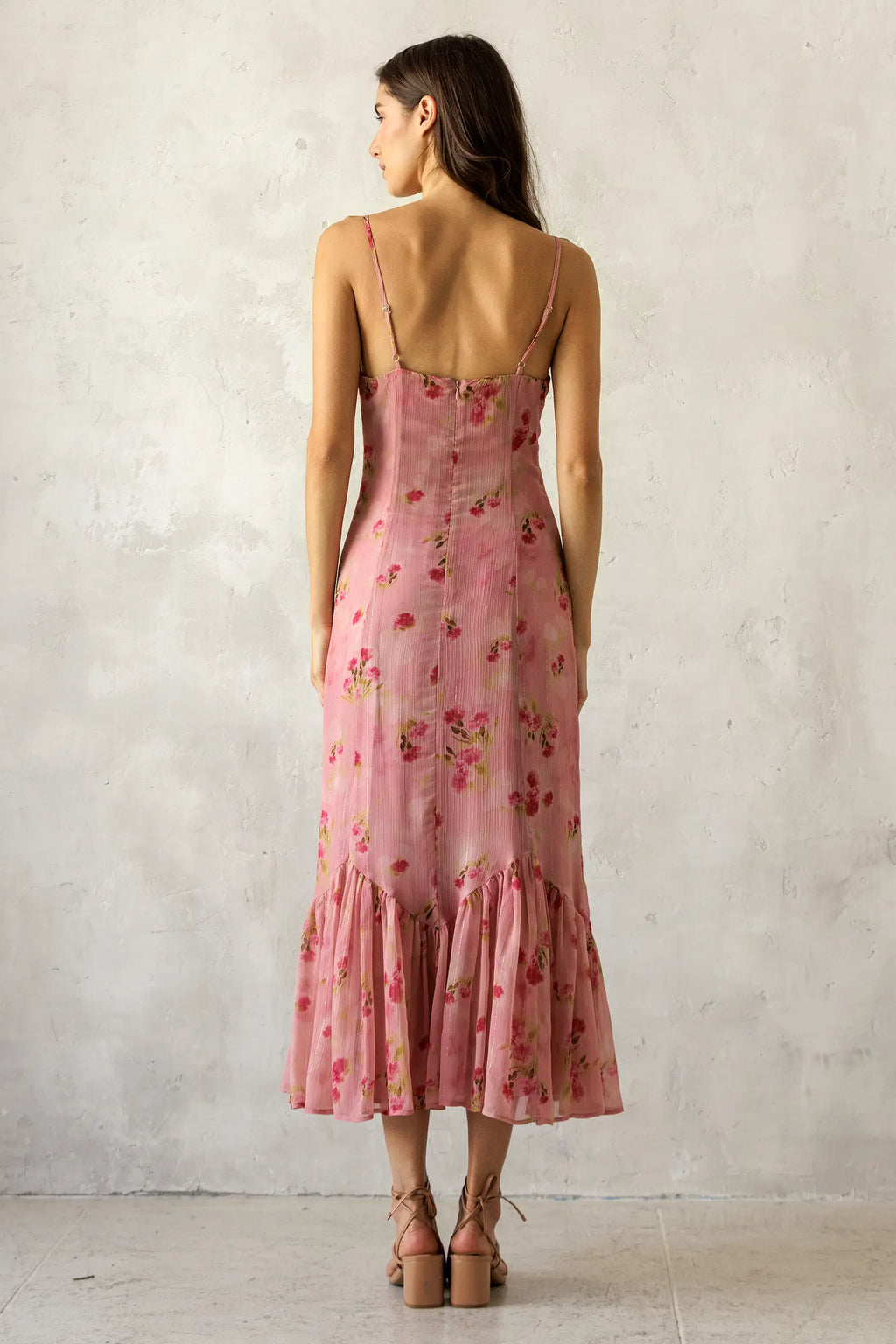 Woman wearing a pink floral dress against a plain background