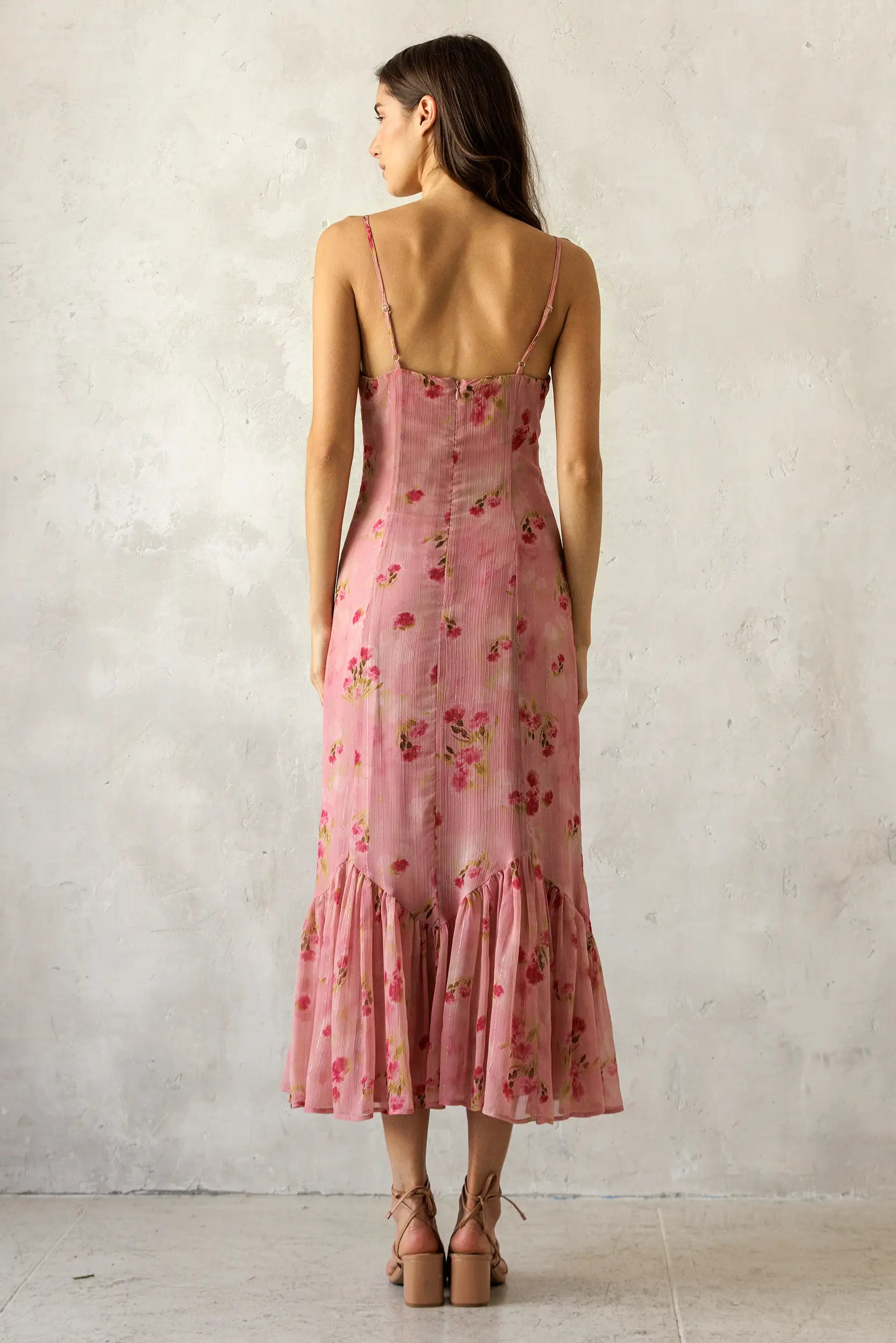 Woman wearing a pink floral dress against a plain background