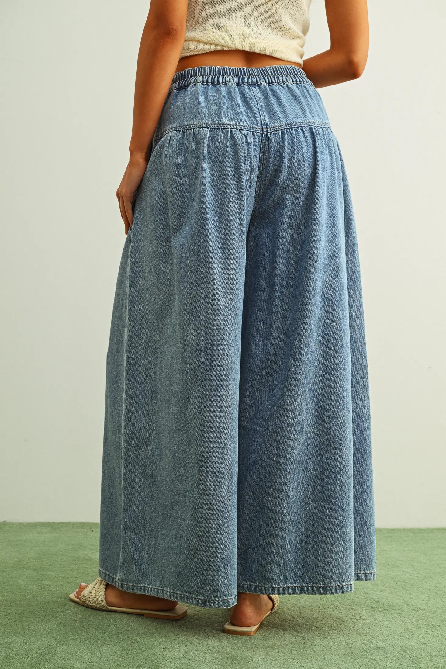 Person wearing blue denim wide-leg pants on a plain background