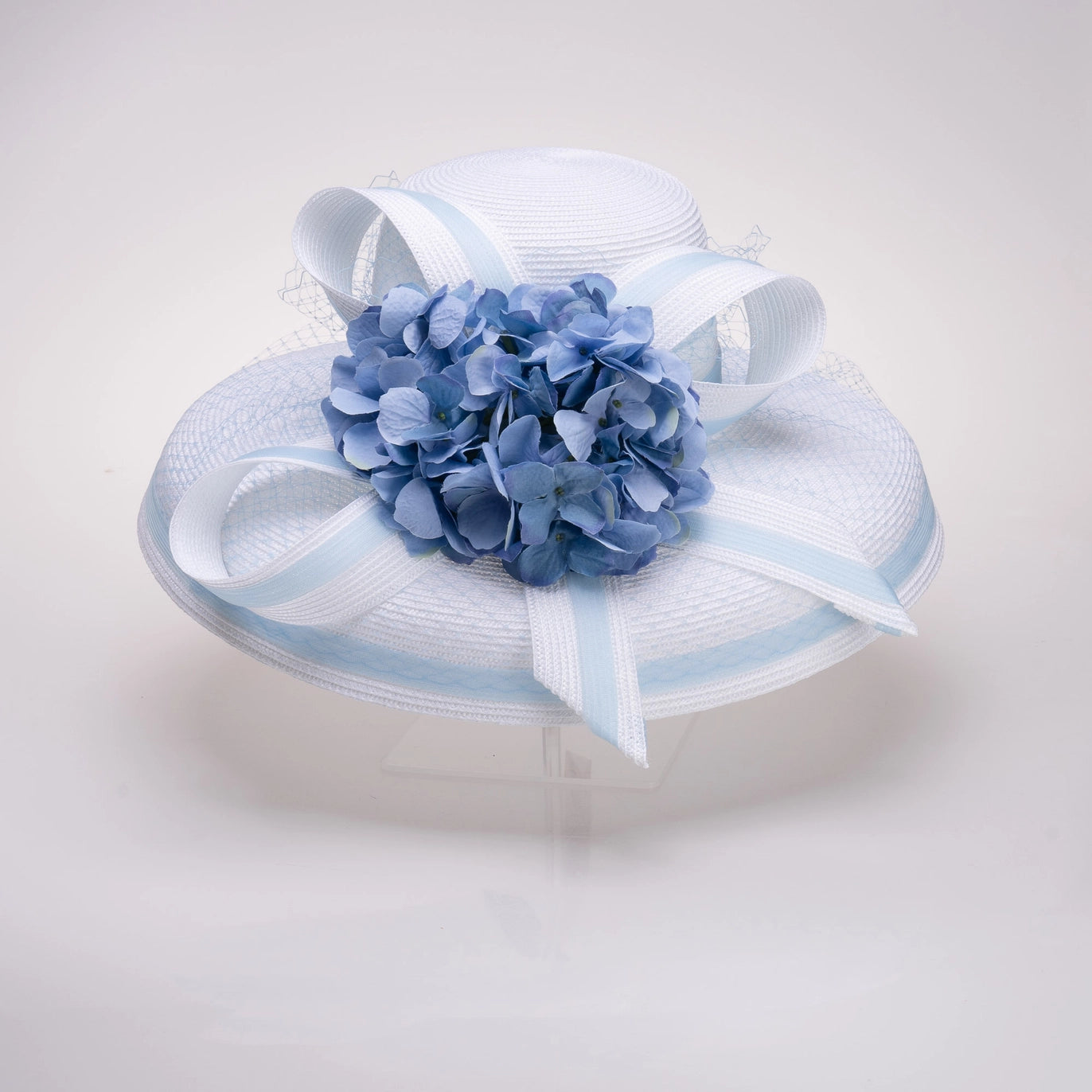 White hat with blue flower and ribbon on a light gray background