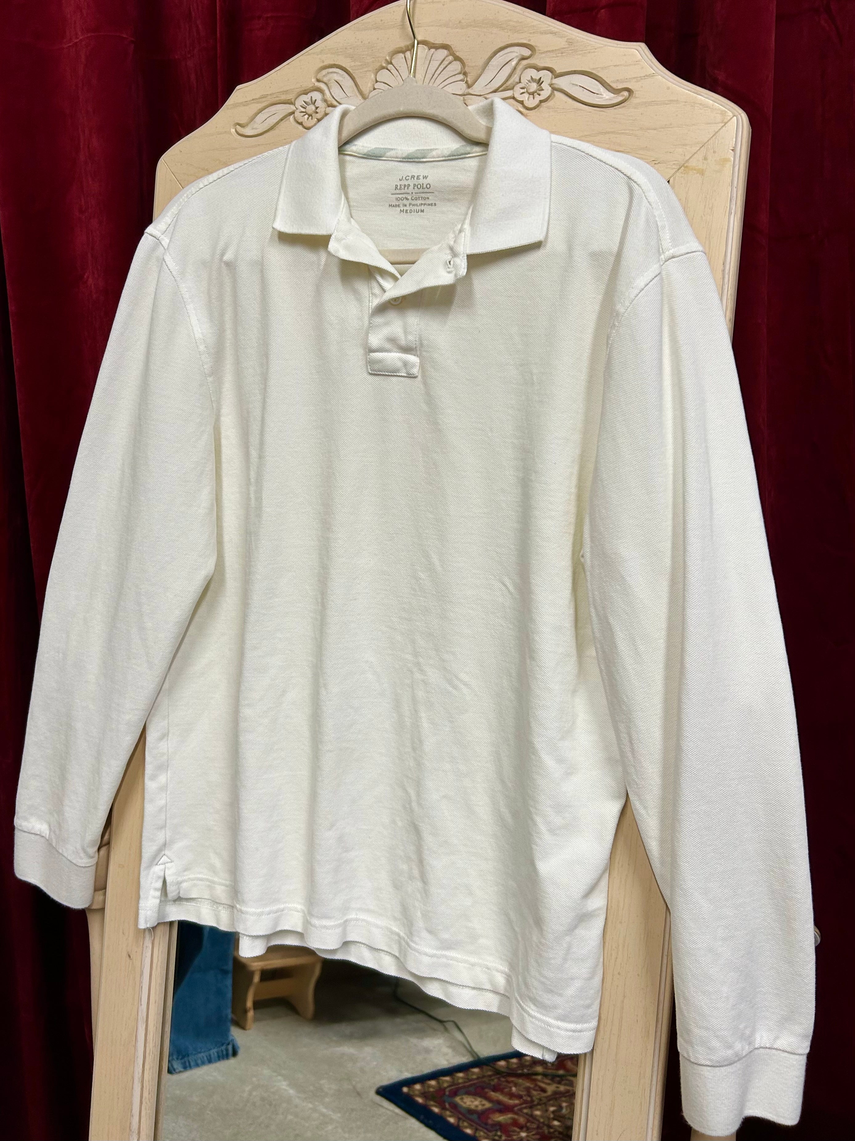 White long-sleeve shirt on a hanger against a red curtain background