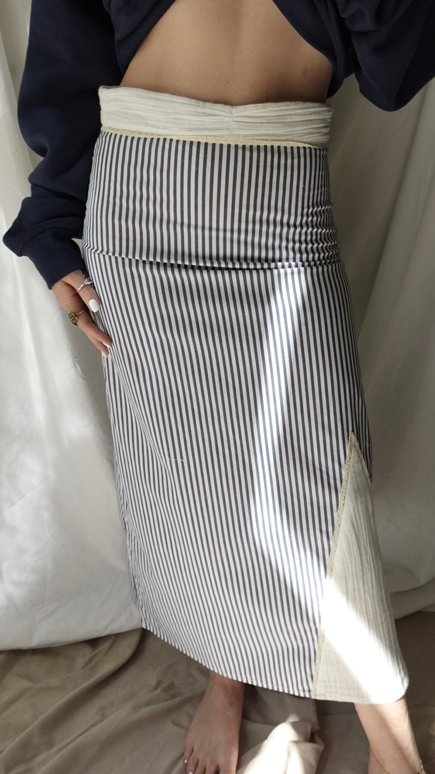 Person wearing a black and white striped skirt with a plain background