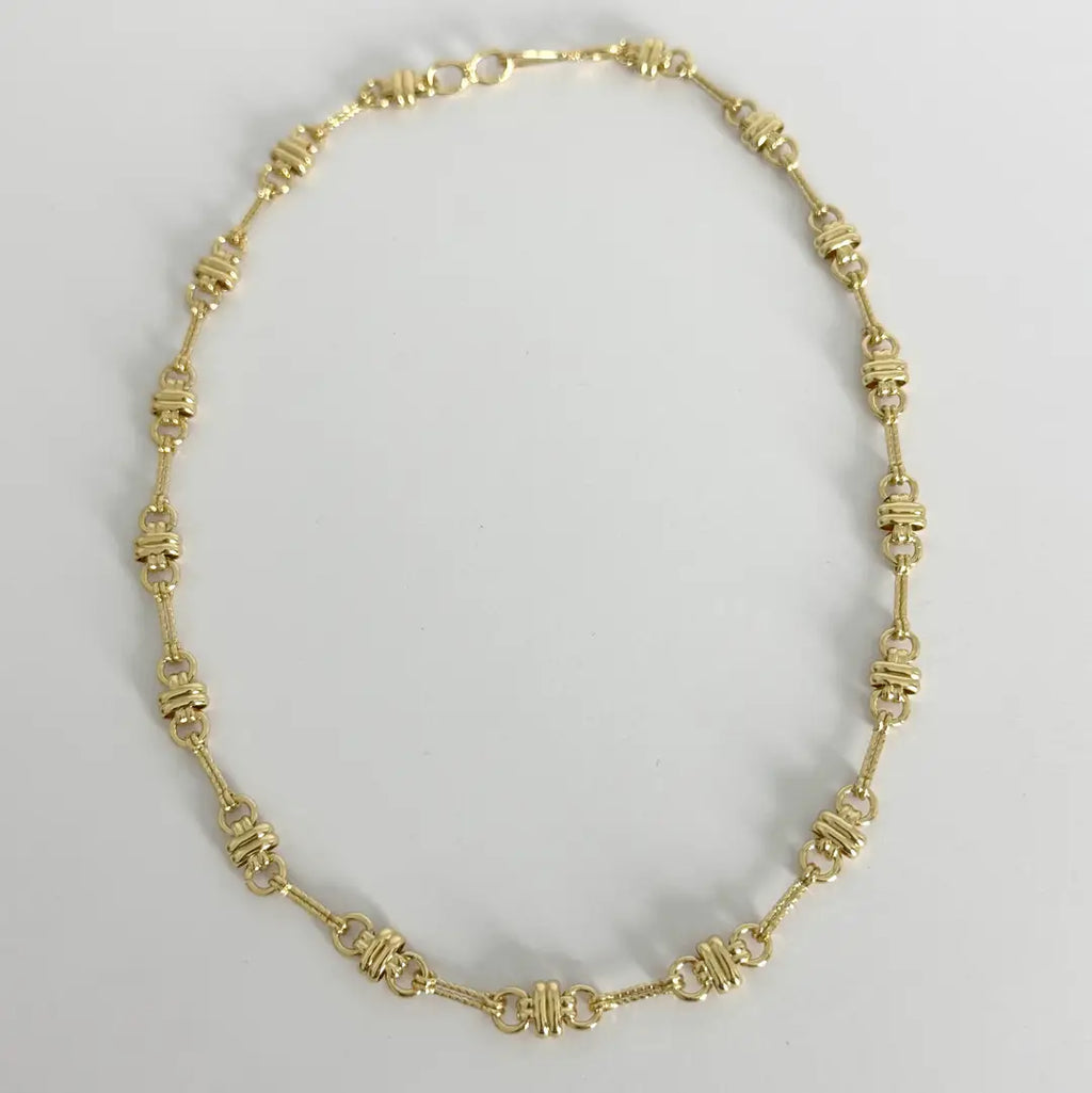 Gold necklace on a light gray background