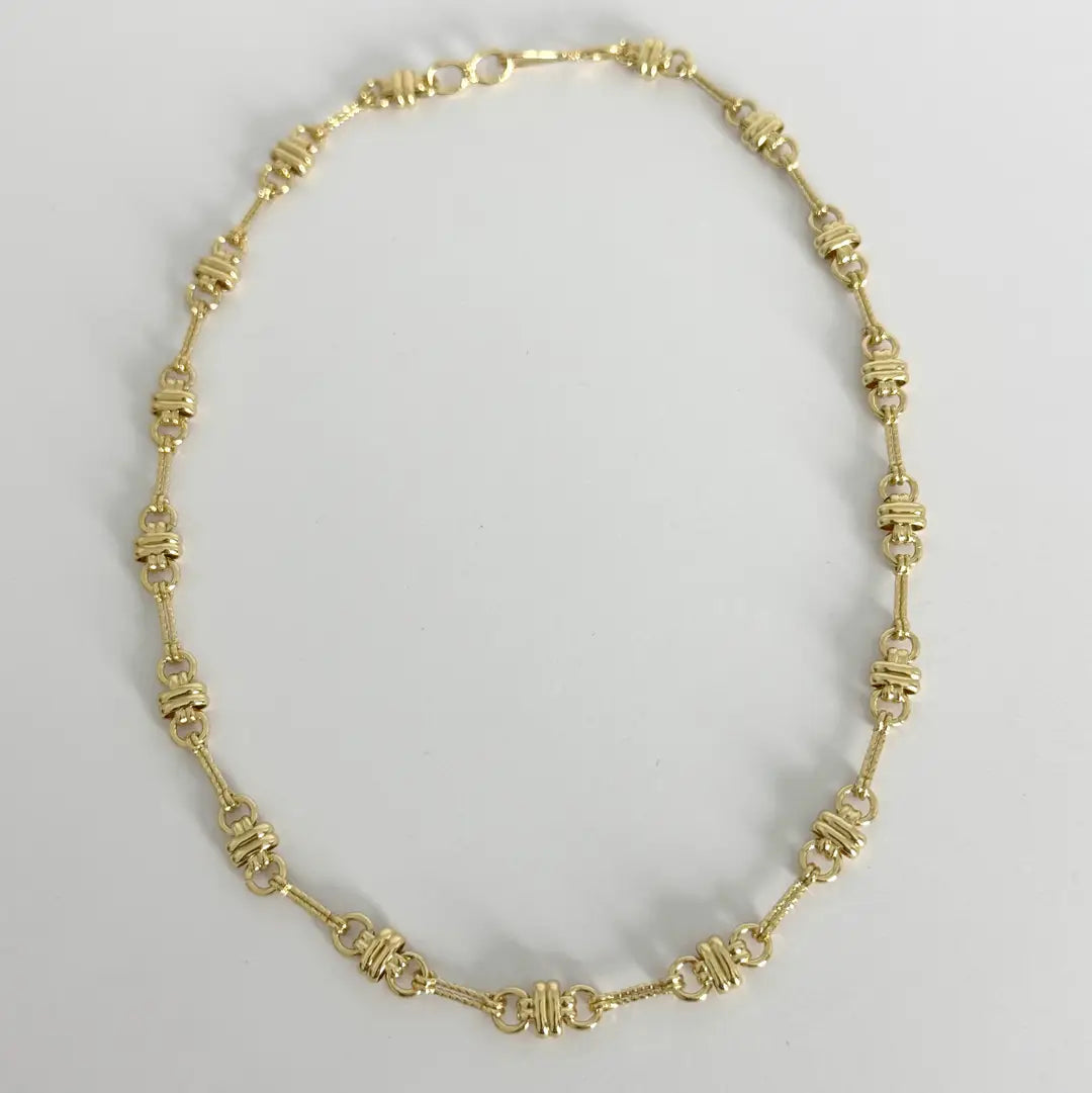 Gold necklace on a light gray background