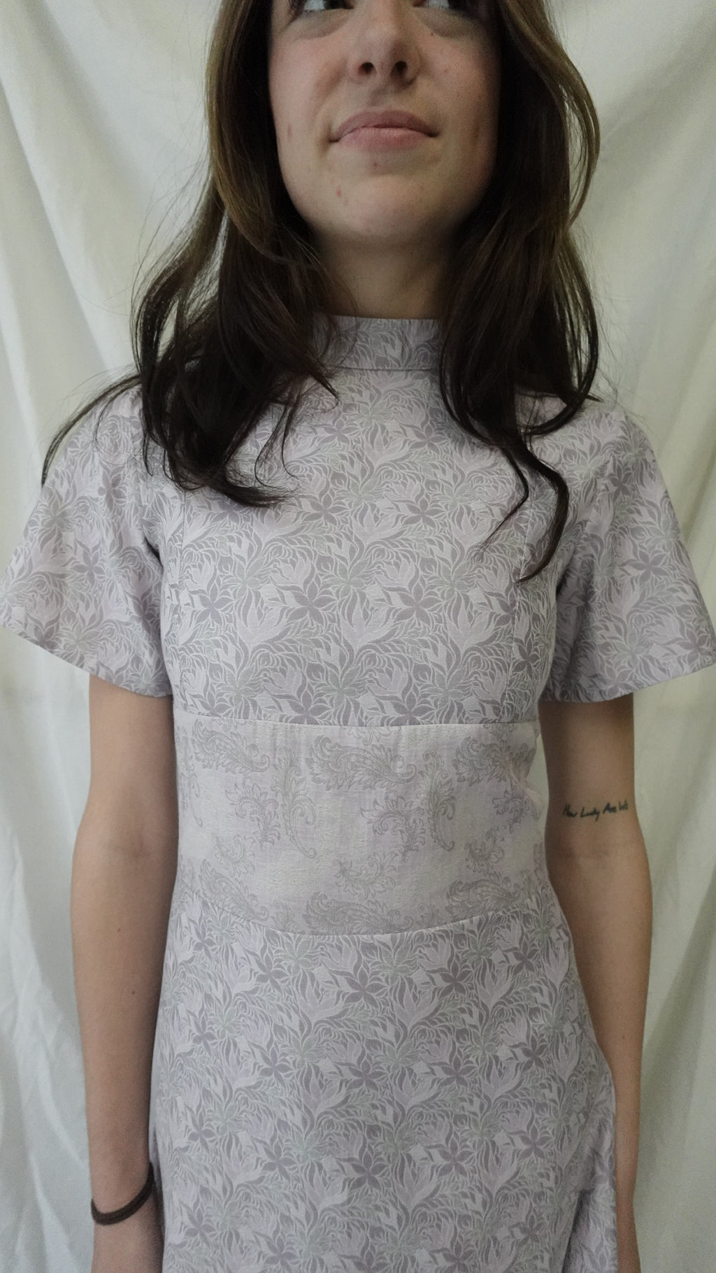 Woman wearing a gray floral dress lying on a white surface
