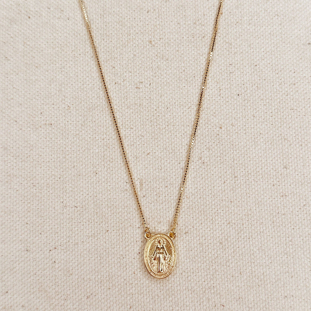 Gold necklace with a pendant on a beige fabric background