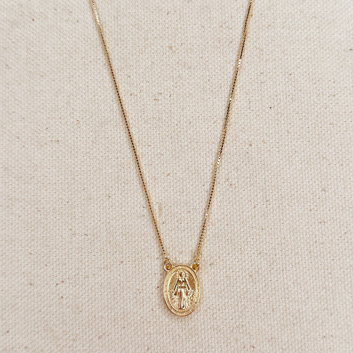 Gold necklace with a pendant on a beige fabric background