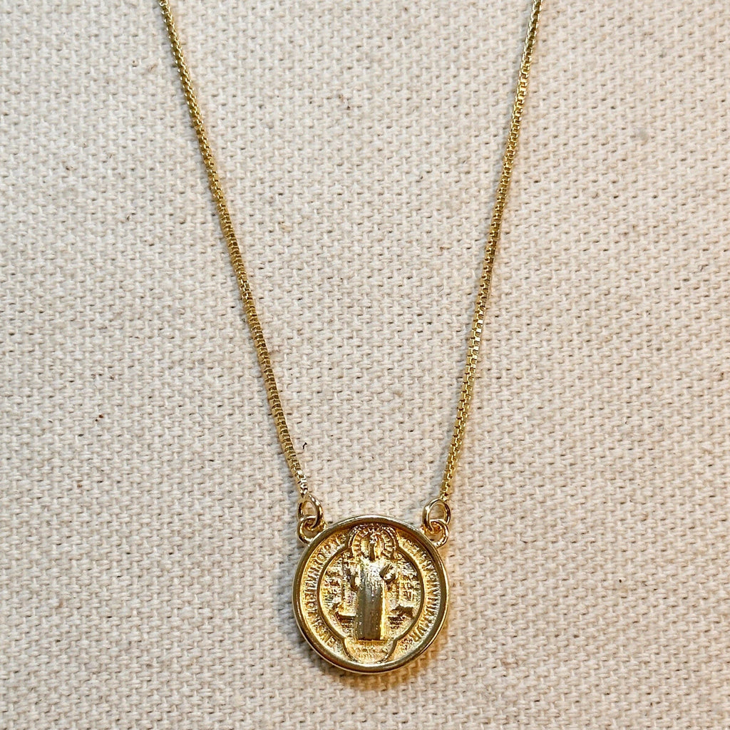 Gold necklace with a round pendant on a beige fabric background