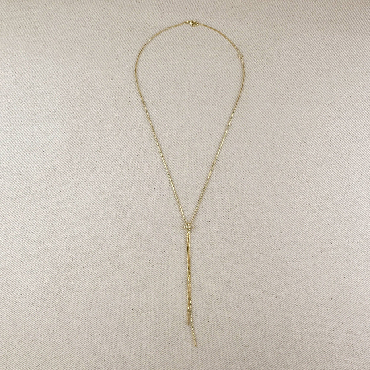 Gold necklace on a beige fabric background