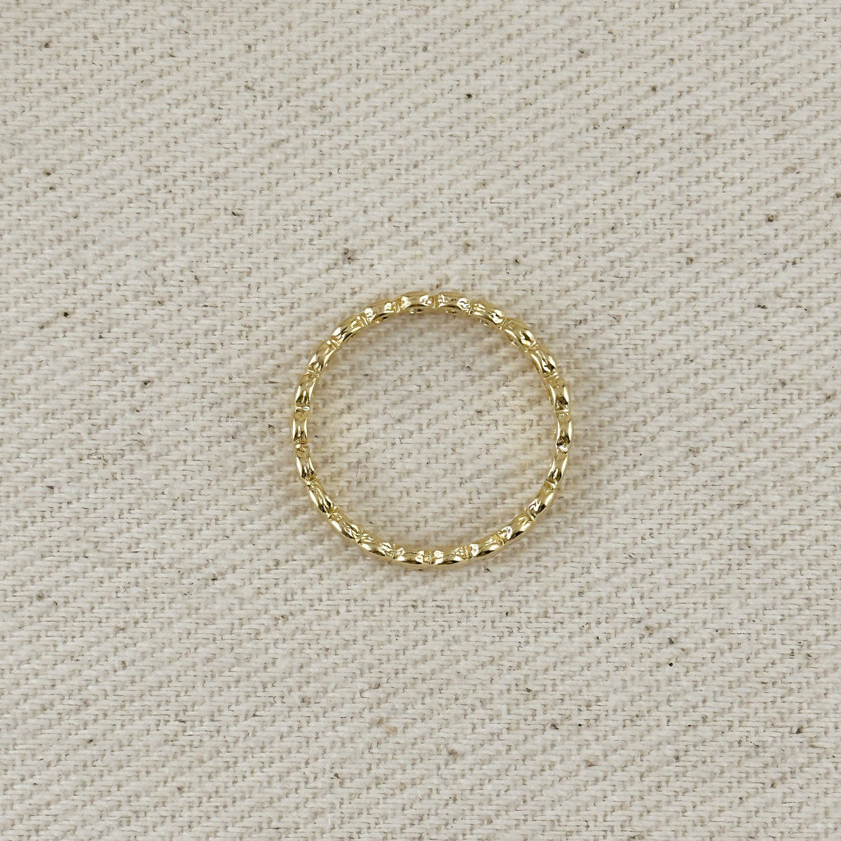 Gold ring on a textured beige background