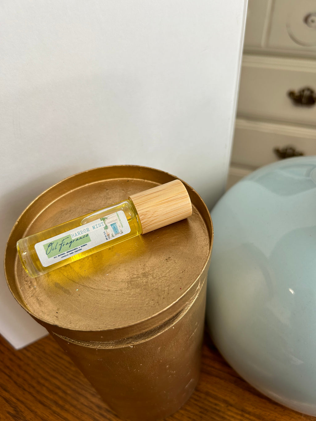 Small bottle of oil with a wooden cap on a gold tray, with a blurred background