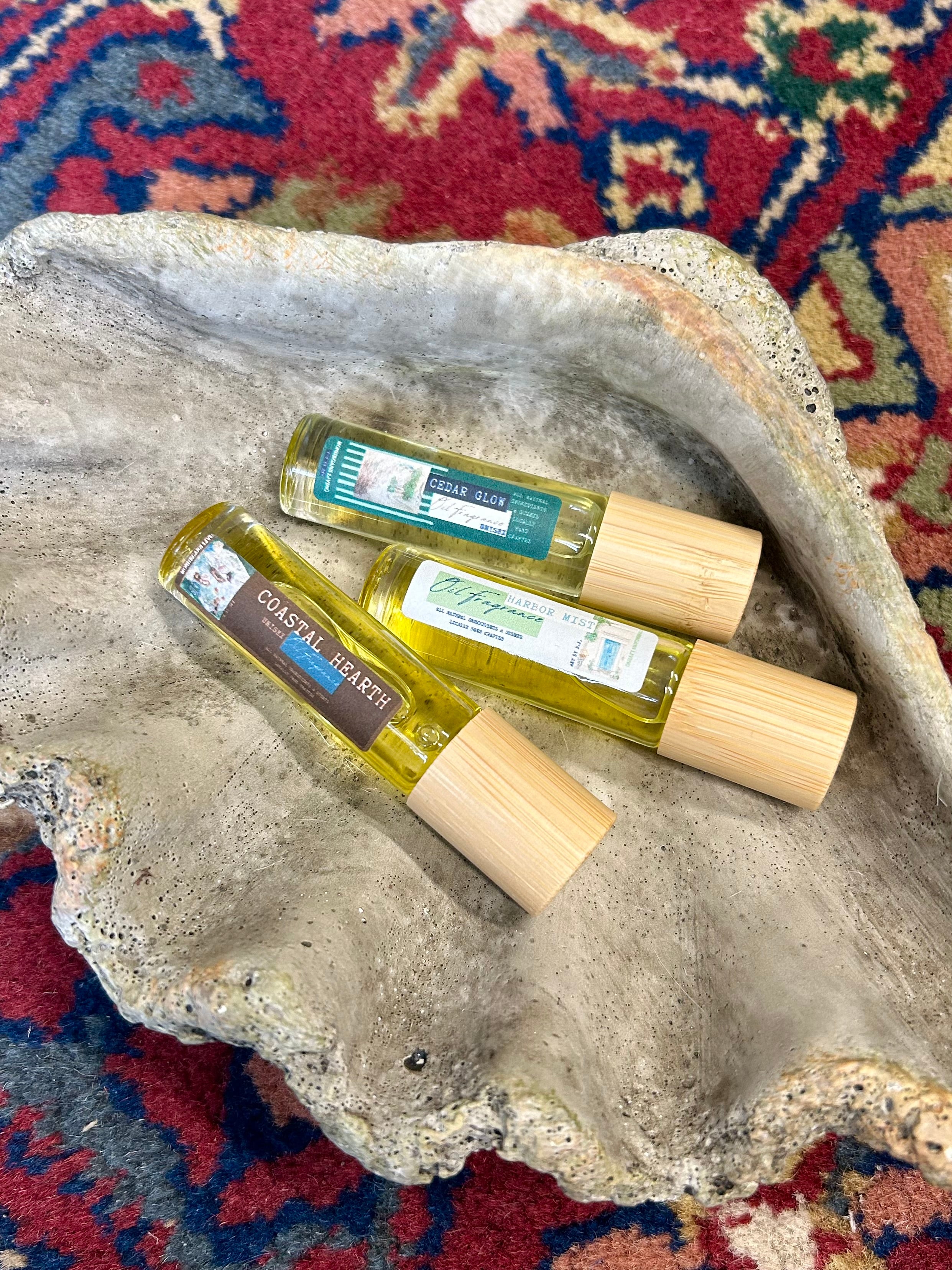 three small bottles with wooden caps on a textured stone surface with a colorful rug background.
