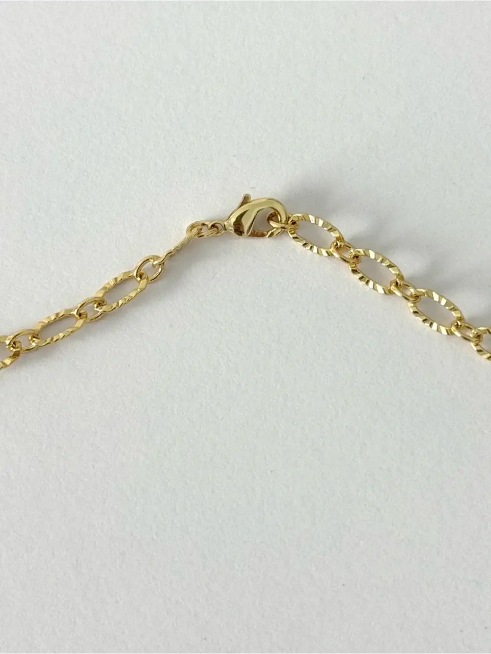 Gold chain bracelet on a light gray background