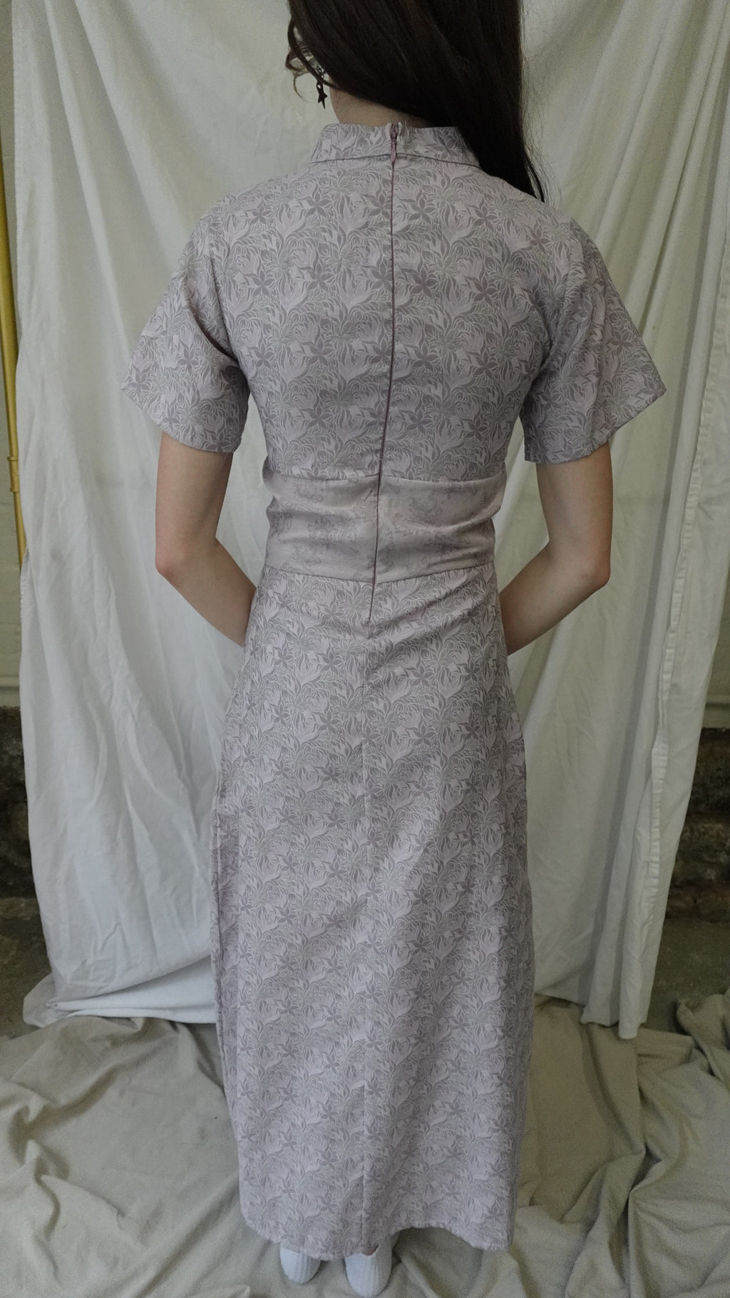 Person wearing a textured gray dress with a white background