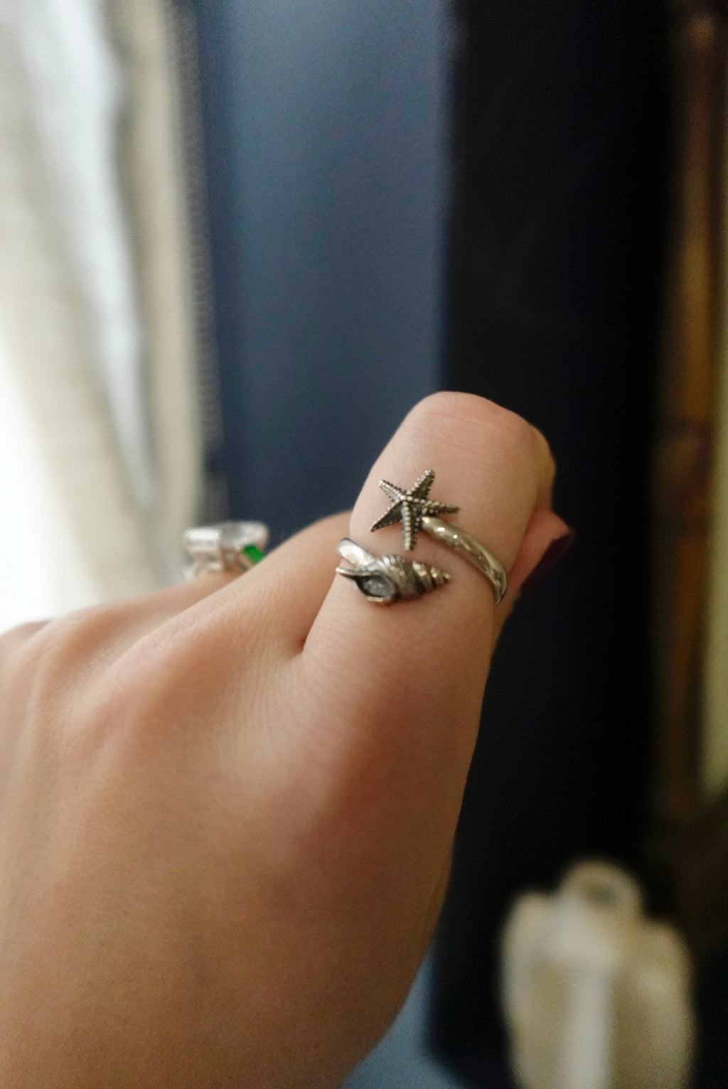 Hand wearing multiple rings with starfish designs against a blurred background