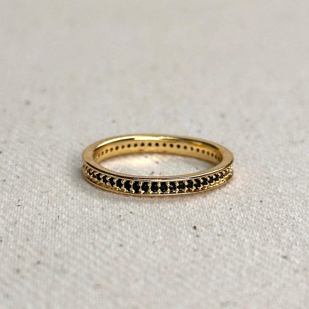 Gold ring with black stones on a light gray background