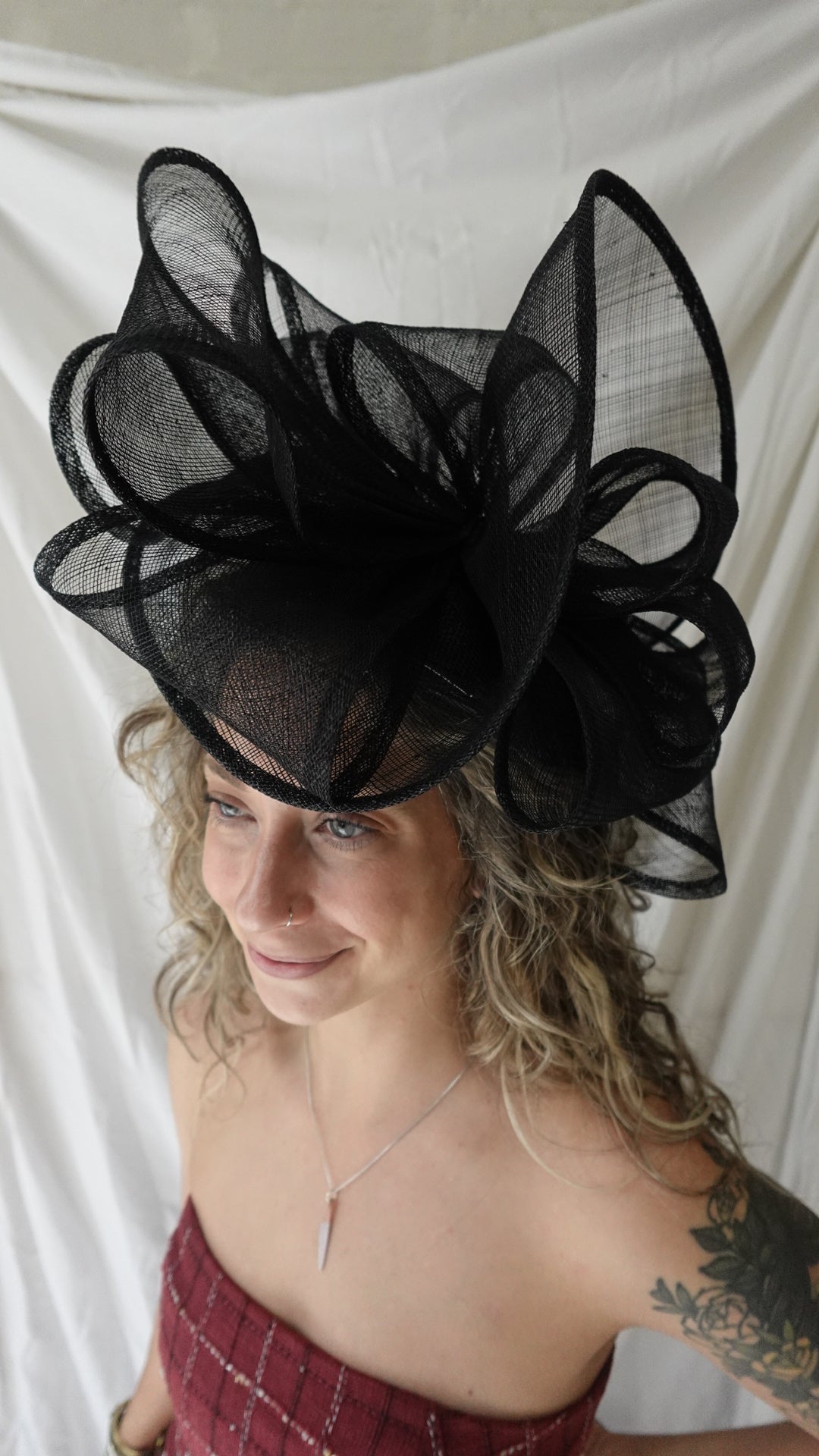 Woman wearing a large black feathered headpiece against a white background