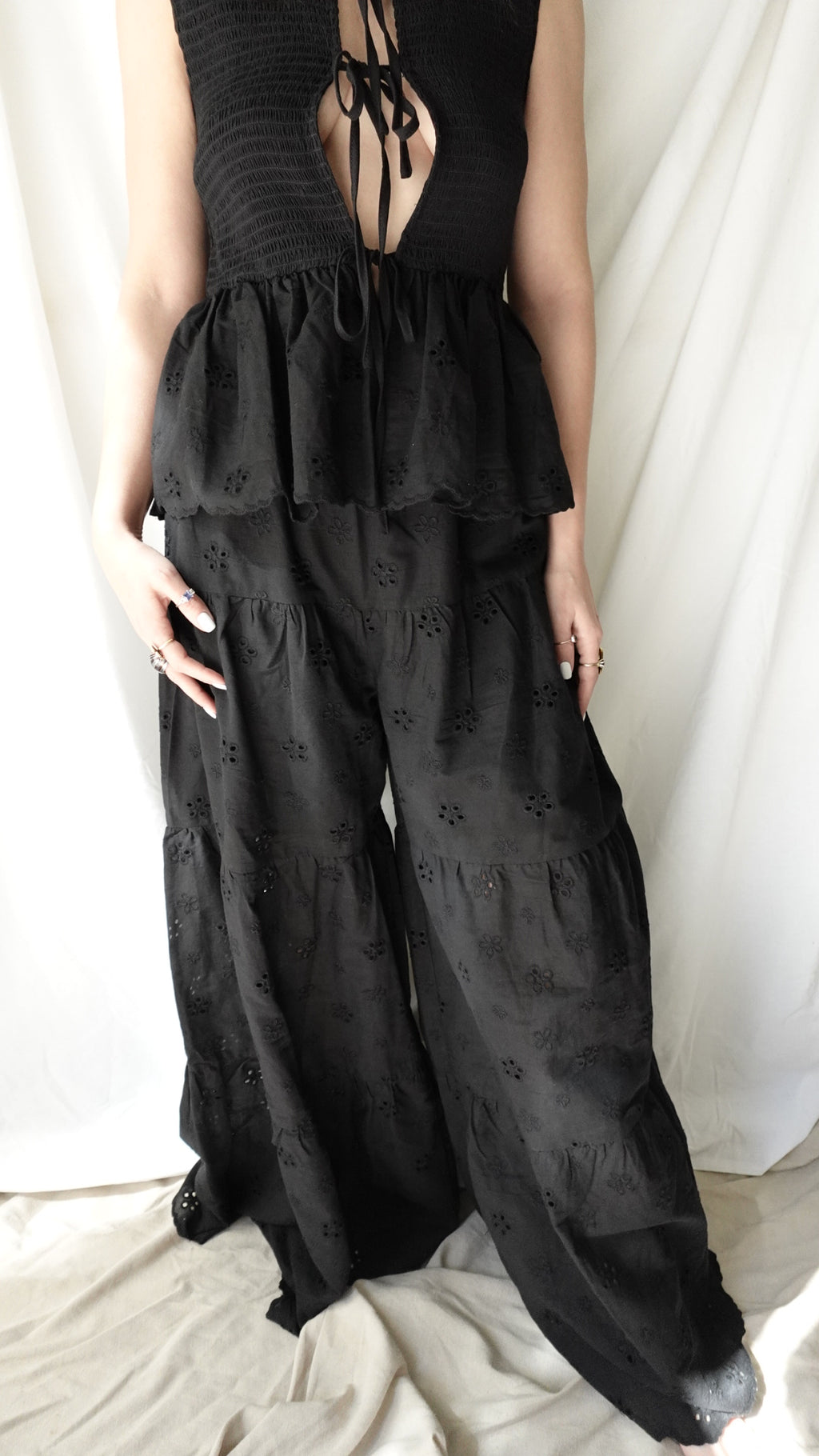 Person wearing a black dress with lace-up sides, standing against a neutral background.