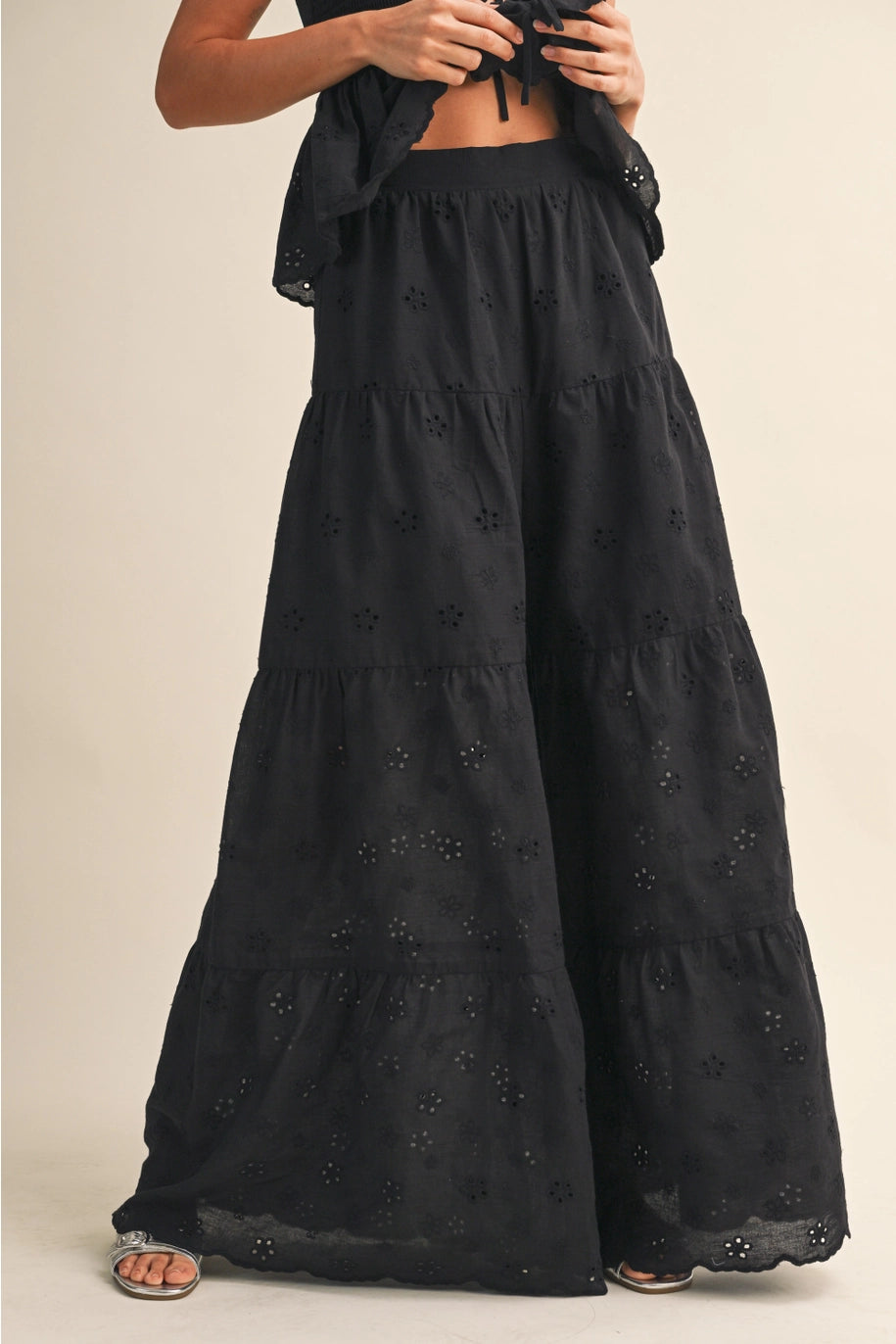 Black tiered dress with intricate detailing on a beige background