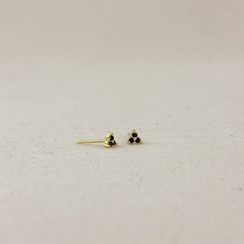 Gold earrings with black stones on a light gray background
