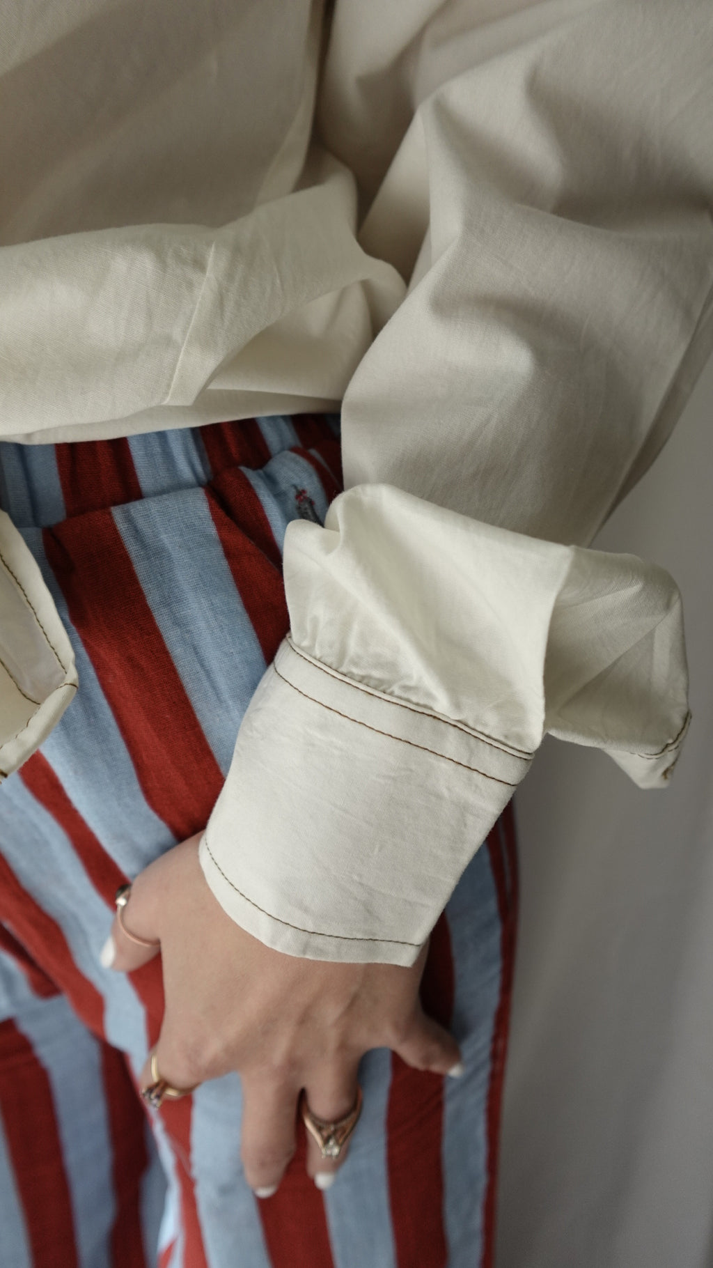 Close-up of a person's hand wearing a ring on a striped fabric background