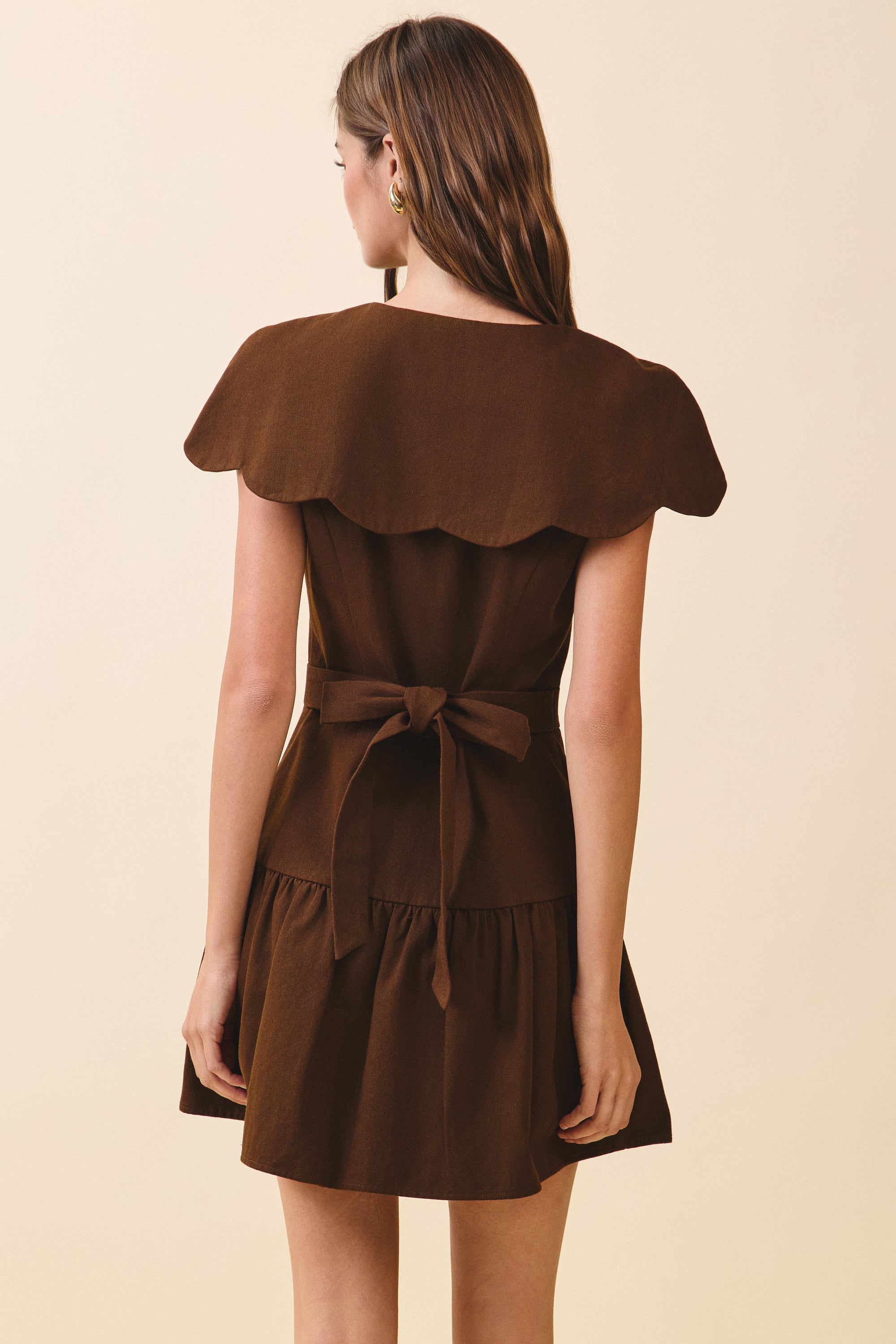 Brown dress with a ruffled neckline on a beige background