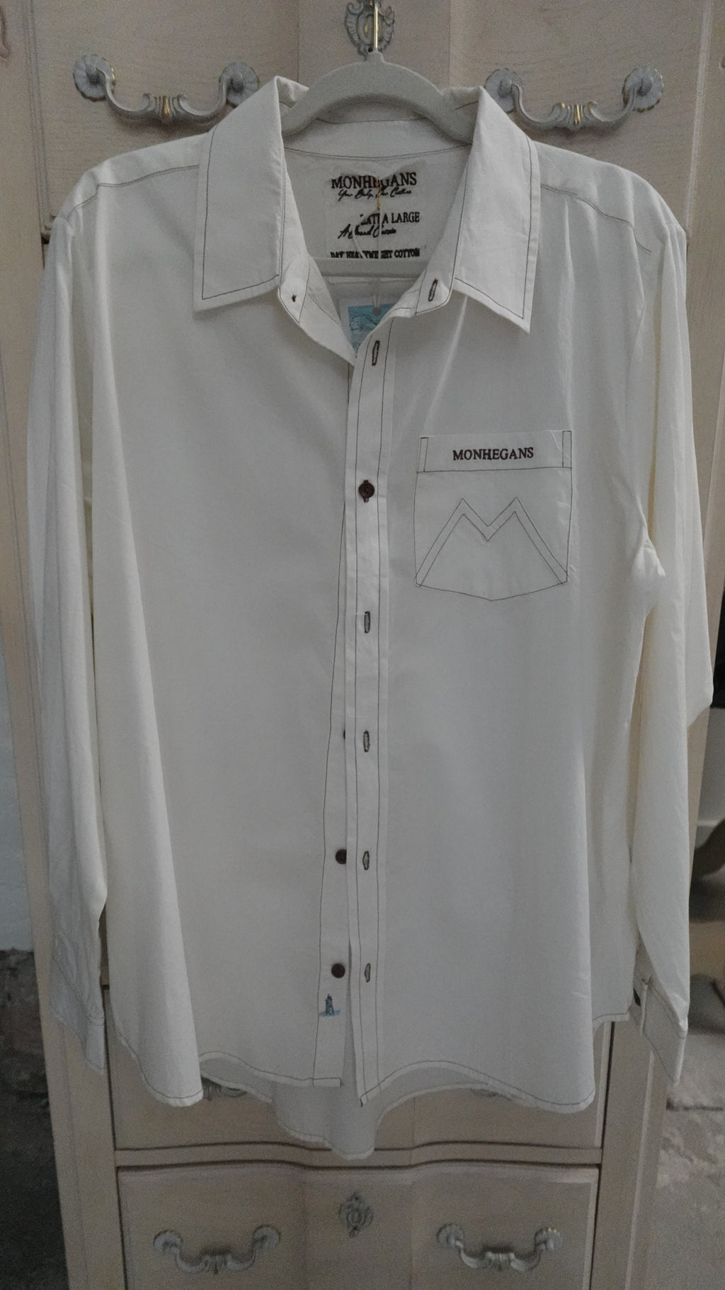 White shirt on a hanger with visible branding on a neutral background