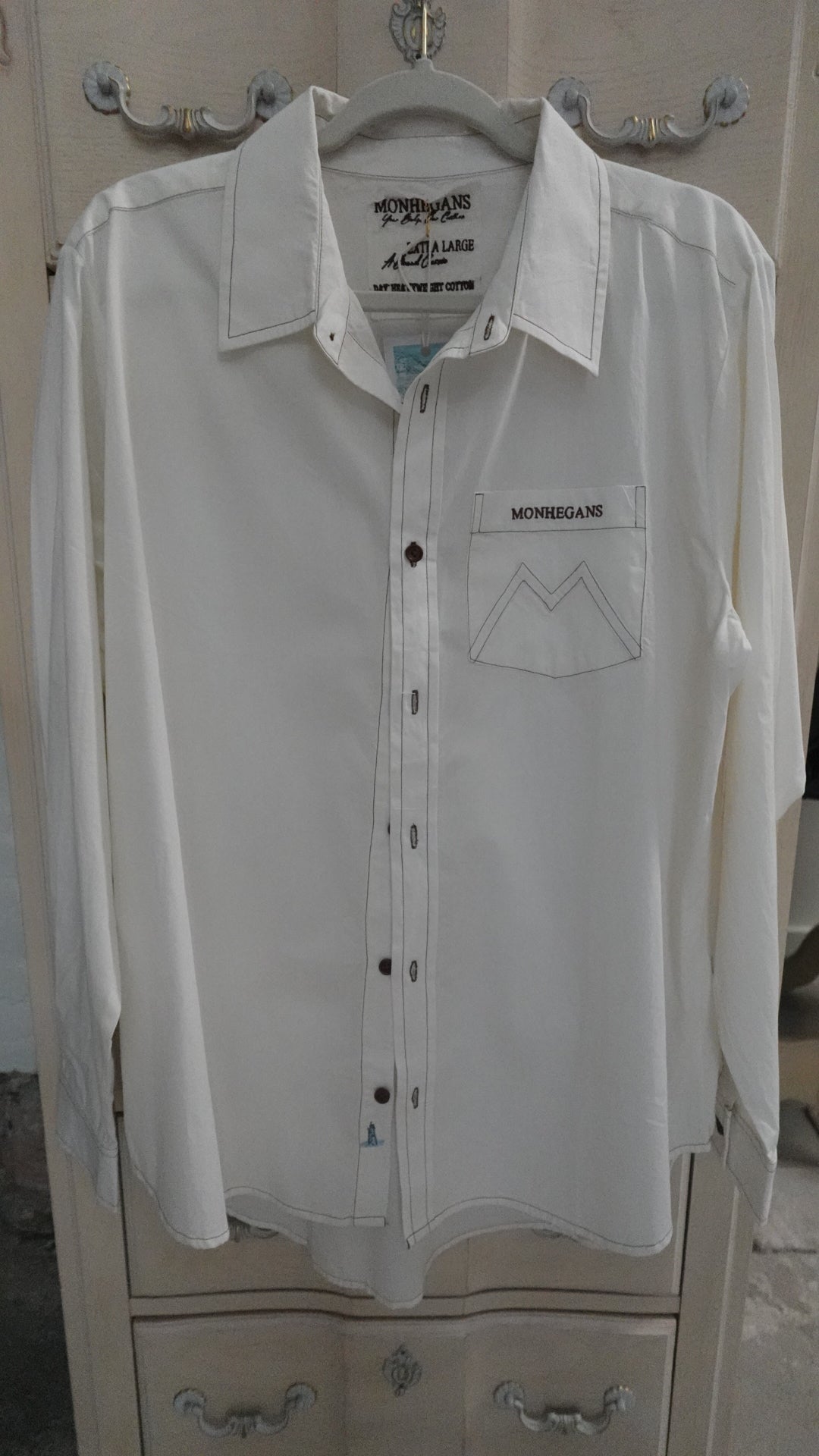 White shirt on a hanger with visible branding on a neutral background