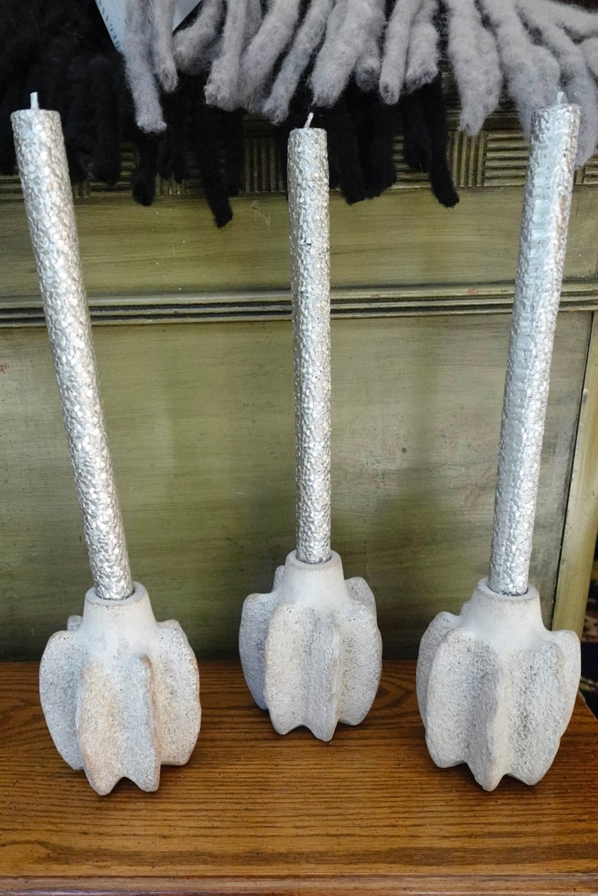 Three decorative candles with textured silver holders on a wooden surface.